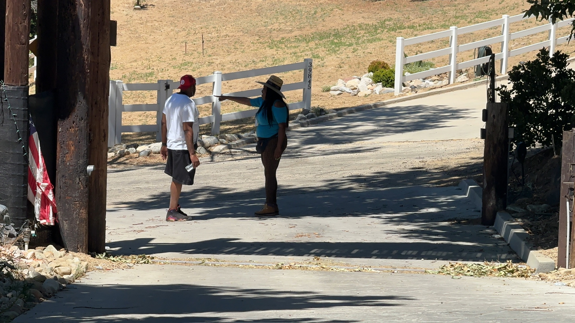 Director on the Dogbelly set pointing out blocking for an actor at a driveway gate.
